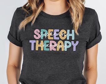 Puede incluir: Una camiseta gris oscuro con el texto "SPEECH THERAPY" en letras de colores con un contorno punteado.