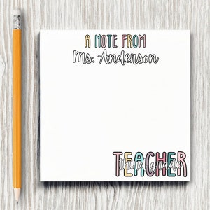 May include: A white notepad with a colorful "A Note From" header and the name "ms. Anderson" written in black. The notepad also has the word "Teacher" written in colorful letters with the words "third grade" written underneath in smaller letters.