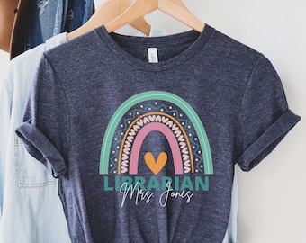 Puede incluir: Una camiseta azul marino con un diseño de arcoíris y el texto "Librarian Mrs. Jones".