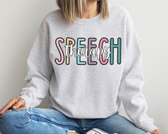 May include: A gray sweatshirt with the text "SPEECH therapy" in colorful letters. The letters are outlined in black and have a slightly rounded font.