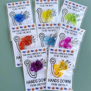 May include: Eight small bags with colorful plastic hands and the text "This Halloween is going to be the best."  Two bags have the text "Hands Down!" and "From: Greyson".