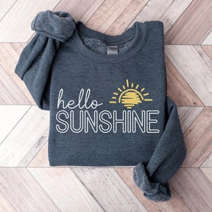 May include: A dark gray sweatshirt with the text "hello sunshine" in white outlined letters and a yellow sun graphic.