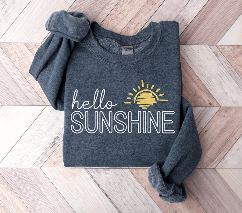 May include: A dark gray sweatshirt with the text "hello sunshine" in white outlined letters and a yellow sun graphic.