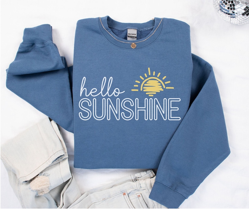 May include: A blue sweatshirt with a white outline of the text "hello sunshine" and a yellow sun graphic.