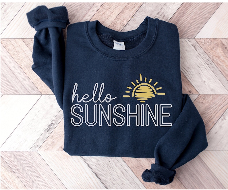May include: A navy blue sweatshirt with a white outline of the text "hello sunshine" and a yellow sun graphic.