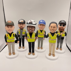 May include: Six custom-made figurines of men wearing yellow safety vests and hard hats. The figurines are standing on individual bases.