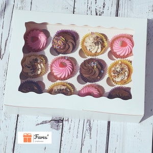 Könnte beinhalten: Eine weiße Backbox mit einem wellenförmigen Fenster, gefüllt mit einem Dutzend Cupcakes. Die Cupcakes haben farbenfrohes Frosting und Streusel. Die Cupcakes befinden sich in gelben, rosa, lila und braunen Cupcake-Formen. Das Logo "Faves' Craftnmor" ist sichtbar.