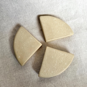 Op de afbeelding: Drie beige keramische tegels, elk in de vorm van een kwartcirkel, met een gespikkelde textuur. De tegels zijn in een cirkel gerangschikt, met de punten van elke tegel die in het midden samenkomen.