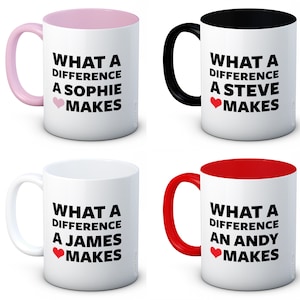 May include: Four white ceramic mugs with different coloured rims and handles. Each mug has black text that reads "What a difference a [name] makes" with a red heart symbol. The names are Sophie, Steve, James, and Andy.