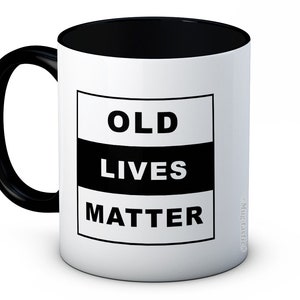May include: White ceramic mug with a black rim and handle. The mug has a black square with the text "OLD LIVES MATTER" in white.