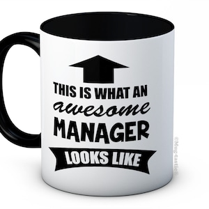 May include: White ceramic coffee mug with a black handle and black rim. The mug has a black graphic that says "This is what an awesome manager looks like" with an arrow pointing up.
