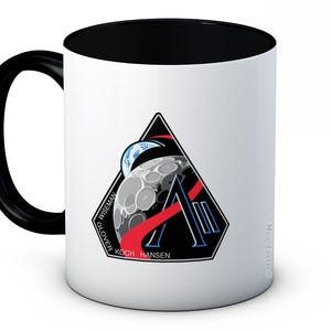 May include: White ceramic mug with a black handle and interior. The mug features a black, red, and white graphic of a moon, Earth, and a stylized letter "A". The names "WISEMAN", "GLOVER", "KOCH", and "HANSEN" are printed on the mug.