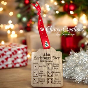 May include: Wooden Christmas Dice game with a red ribbon. The game features instructions for a gift exchange, including "Keep Gift," "Pass Gift Right," and "Unwrap Gift." The ribbon is decorated with snowflakes and Christmas trees.
