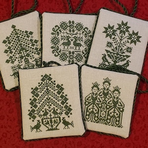 Pode incluir: Cinco enfeites de Natal feitos à mão em verde e branco com um design escandinavo tradicional. Cada enfeite apresenta um design diferente, incluindo uma árvore, uma estrela e um pássaro.