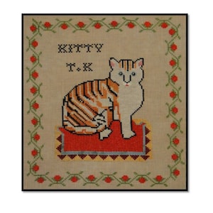May include: A cross-stitch embroidery of an orange and white tabby cat sitting on a red rug. The cat is surrounded by a green and red floral border. The text "KITTY T.K." is stitched above the cat.