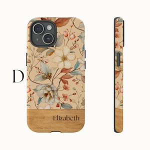 Puede incluir: Una funda para tel&eacute;fono beige y marr&oacute;n con flores, con un fondo de madera y el nombre "Elizabeth" impreso en ella.