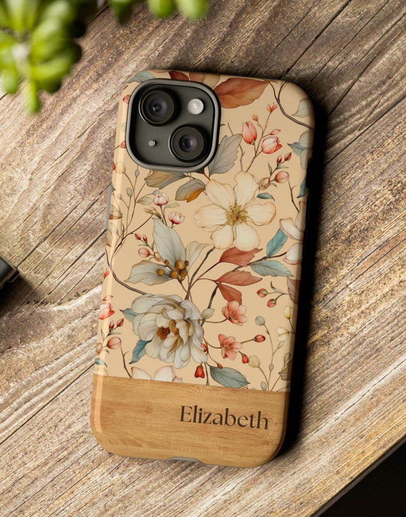 Puede incluir: Una funda para tel&eacute;fono beige y marr&oacute;n con estampado floral, parte inferior de aspecto de madera y el nombre "Elizabeth" grabado.