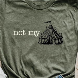 May include: A green t-shirt with the text "not my" and a black and white illustration of a circus tent.