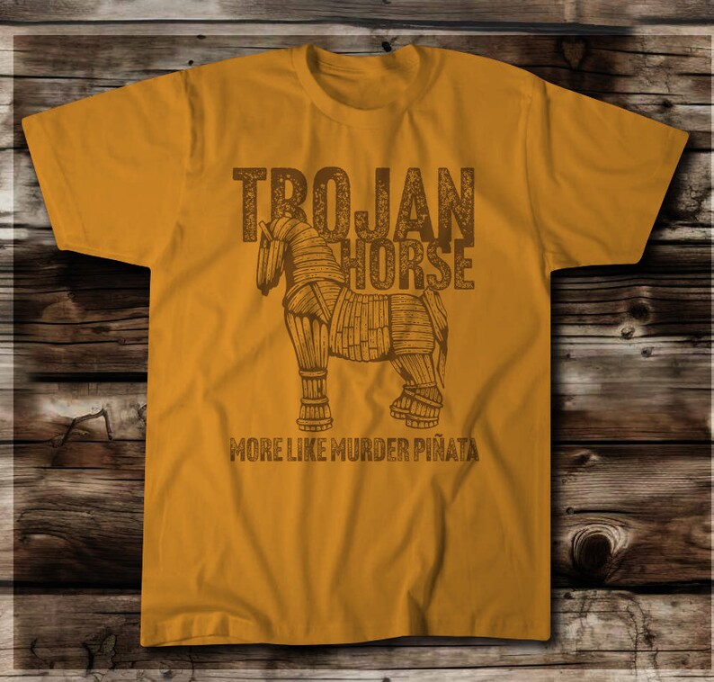 Image of the Trojan Horse (Dark Brown Ink) with the words Trojan Horse….More like Murder Pinata.  On a Next Level Antique Gold shirt