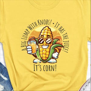 May include: A yellow t-shirt with a cartoon corn wearing sunglasses and holding a glass of orange juice. The text on the shirt reads "A big lump with knobs! It has the juice! It's corn!"