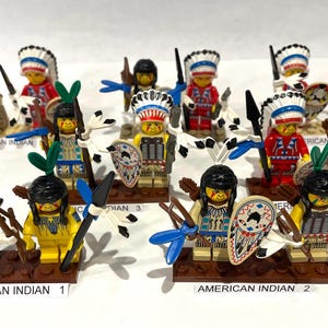 May include: A collection of twelve plastic minifigures arranged in rows, each wearing detailed headdresses and traditional-style clothing. Several figures hold accessories like bows, arrows, spears, and shields. Labels read AMERICAN INDIAN 1, 2, 3, 4.