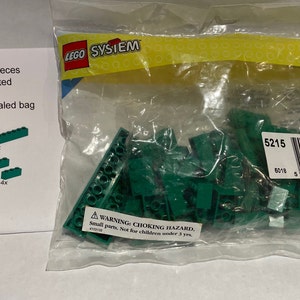 Puede incluir: Una bolsa de plástico que contiene 62 piezas de Lego verdes, etiquetada como "Lego #5215 - 62 piezas Ladrillos verdes surtidos Juego de servicio Nuevo en bolsa sellada de polímero". La bolsa también tiene una etiqueta de advertencia que dice "ADVERTENCIA - RIESGO DE ASFIXIA Piezas pequeñas. No apto para niños menores de 3 años."