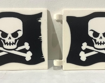 Könnte beinhalten: Zwei weiße Piratenflaggen aus Kunststoff. Jede Flagge zeigt ein schwarzes Totenkopf- und gekreuzte Knochen-Design auf schwarzem Hintergrund. Die Flaggen haben eine rechteckige Form mit einer gebogenen Oberkante.