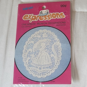 May include: A package of Expressions iron-on decorations. The package is pink with the word "NEW!" in the upper left corner and "99¢" in the upper right corner. The package contains a white lace stroller design on a blue background. The dimensions are 2 14/16" x 3 7/16".