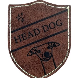 May include: Brown leather patch with a white stitched border in the shape of a shield. The patch has a black outline and the text "HEAD DOG" inside. A black and white illustration of a dog's head is in the bottom half of the patch.