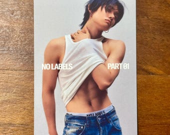 May include: A rectangular photo card featuring a person with dark hair wearing a white tank top pulled up to reveal their midriff and blue denim jeans with a white waistband labelled NO LABELS. The text NO LABELS PART 01 is printed in white.