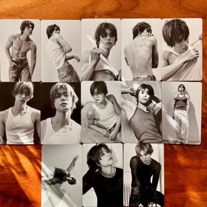 May include: A collection of twelve rectangular photo cards featuring a person with dark hair in various poses and outfits, including white tank tops, dark long-sleeve shirts, and jeans, presented in a black and white monochromatic photographic style.