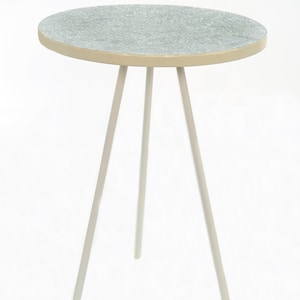 May include: A small, round, light grey side table with a white top and three white legs.