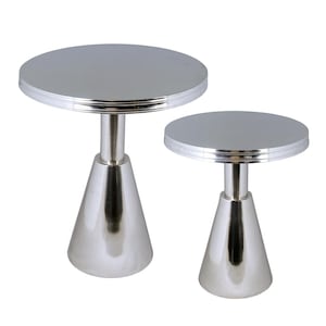 May include: Two silver side tables. Each table has a round top with a decorative edge, supported by a conical base. The tables are made of a shiny, reflective metal.