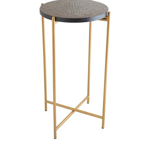 May include: A round side table with a black wood top and a gold metal base. The top has a unique mosaic pattern.