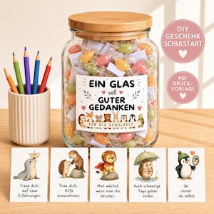 May include: A clear glass jar with a bamboo lid filled with wrapped candies and paper notes, featuring a label that reads "EIN GLAS voll GUTER GEDANKEN FÜR DIE SCHULZEIT" with animal illustrations. Five cards with animal drawings and German text are displayed in front.