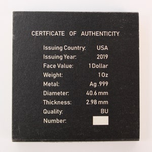 May include: A black certificate of authenticity for a 2019 American Silver Eagle coin. The certificate lists the coin's issuing country, year, face value, weight, metal, diameter, thickness, quality, and number.