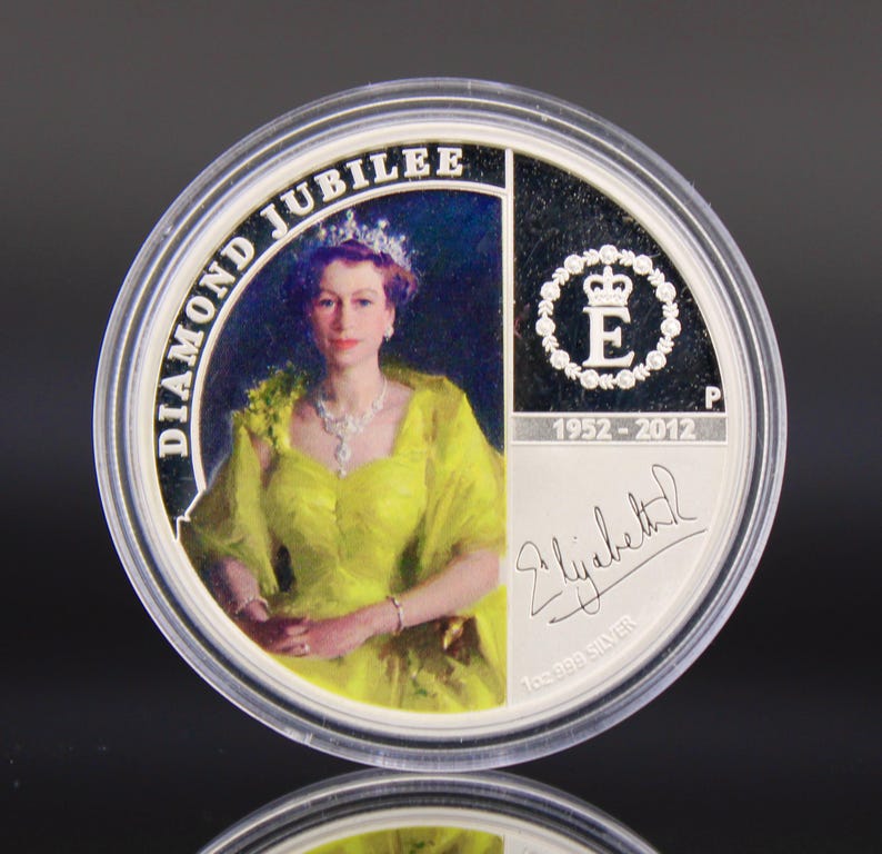 May include: A white ceramic mug with a black handle and the text "But First, Coffee" in a bold, black font. The mug is set against a blurred background, suggesting a cozy setting.