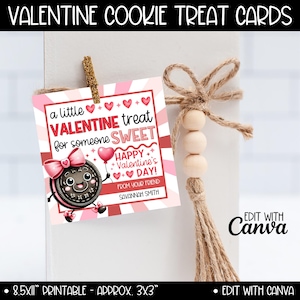 May include: Valentine's Day cookie treat card with a pink and red design. The card features a cartoon cookie with a bow, hearts, and the text "a little Valentine treat for someone sweet." The card is approximately 3x3 inches.