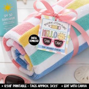 May include: A rolled-up beach towel with pink, white, yellow, blue, and green stripes, tied with a pink ribbon. A tag reads "Goodbye Lesson Plans, Hello Sun Tans" with sunglasses and a sun graphic. A bottle of SPF 50 sunscreen is in the background.