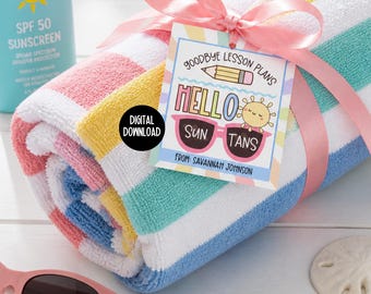 May include: A rolled-up beach towel with pink, white, yellow, blue, and green stripes, tied with a pink ribbon. A tag reads "Goodbye Lesson Plans, Hello Sun Tans" with sunglasses and a sun graphic. A bottle of SPF 50 sunscreen is in the background.