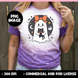 May include: Purple and white t-shirt with a cartoon ghost holding a black cat. The ghost has an orange bow and is surrounded by stars, moons, and bats. The shirt has a bleached effect and the text "PNG IMAGE".
