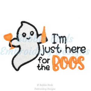 Op de afbeelding: Een wit spook met een vriendelijk gezicht houdt een glas wijn in de ene hand en een kegel in de andere. De tekst "I'm just here for the boos" is geschreven in zwart en oranje.