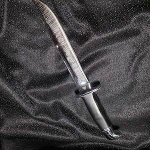 Pode incluir: Uma faca de lâmina fixa com cabo de metal prateado polido e uma lâmina de aço curva e afiada. A lâmina apresenta uma textura de metal escovado visível e o ricasso está estampado com o texto BUCK USA, indicando o fabricante.