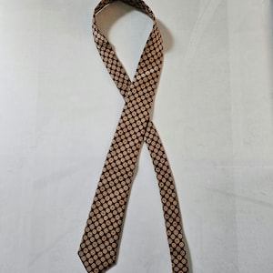 May include: A brown tie with a tan and white geometric pattern.