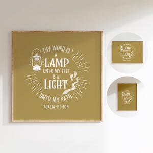 May include: A framed print with the text "THY WORD IS A LAMP UNTO MY FEET & A LIGHT UNTO MY PATH. PSALM 119:105". The artwork features a lantern illustration and a path of footprints. The background is a muted olive green.