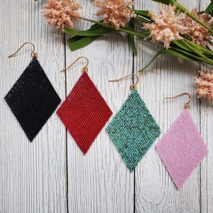 Puede incluir: Cuatro pares de pendientes en forma de diamante en negro, rojo, turquesa y rosa.