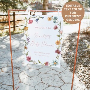 Pu&ograve; includere: Un cartello rettangolare bianco appeso a una cornice di rame, decorato con un bordo floreale ad acquerello colorato. Il testo recita: WELCOME TO, Scarletts, Baby Shower, SEPTEMBER 16, 20XX, San Diego, California. Un cerchio marrone contiene il testo: EDITABLE TEXT COLOR FOR DIFFERENT GENDERS.