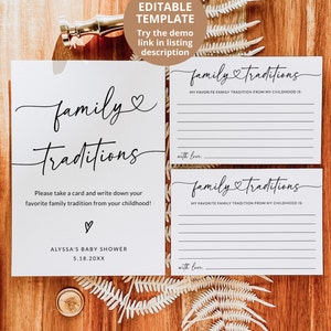 May include: Two white cards with black text that reads "family traditions". The cards have lines for guests to write down their favorite family traditions from their childhood. The cards are on a wooden surface with a fern.