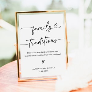 May include: A gold-framed sign with white background and black text that reads "family traditions". The sign also includes the text "Please take a card and write down your favorite family tradition from your childhood!" and "ALYSSA'S BABY SHOWER 5.18.20XX".