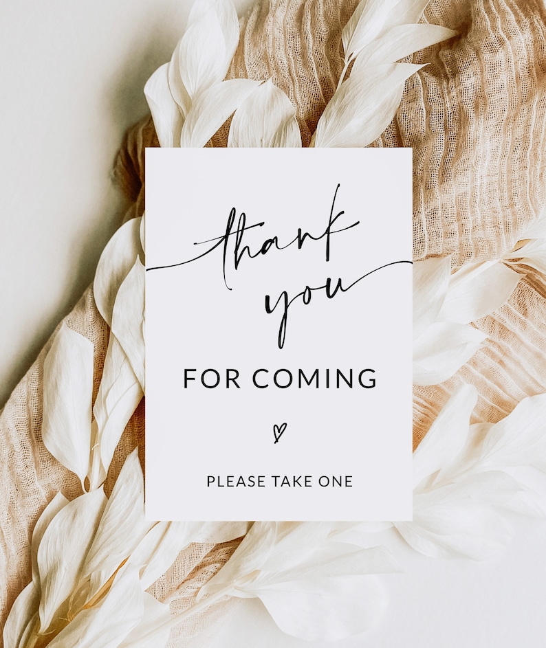 May include: White card with black calligraphy that says "thank you for coming" with a heart symbol and the text "please take one" at the bottom. The card is on a white and brown background.